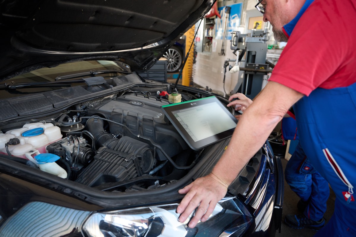 Fehlerdiagnose mit Tablet am geöffneten Motorraum