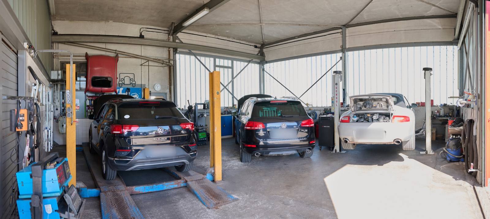 Werkstatthalle mit mehreren Fahrzeugen auf Hebebühnen